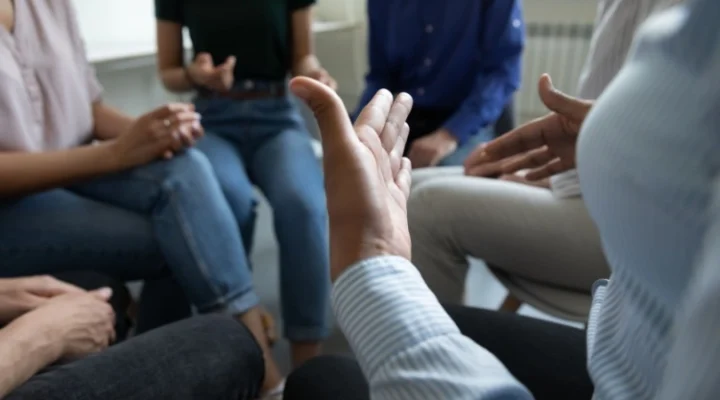 a group of people sitting in a circle sharing thoughts and feelings during mental health treatment